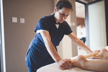 Massage therapist using wooden tool to massage patient