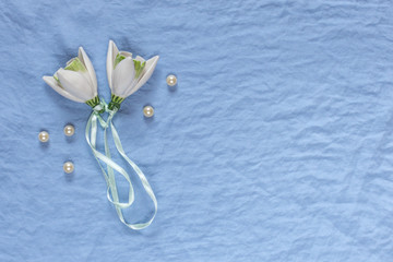 Wedding decor. White ceramic flowers, pearls on a blue fabric background. Template for wedding greeting cards