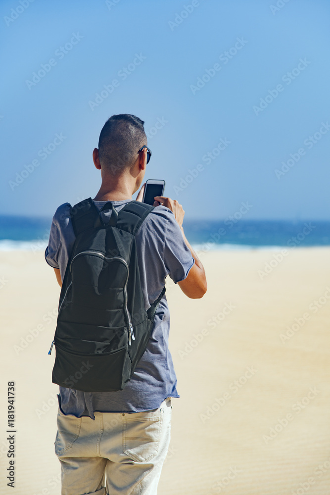 Wall mural young man using a smartphone outdoors