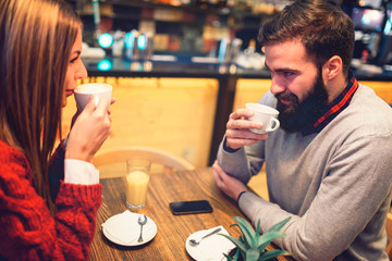 Beautiful couple drinking coffee talking and having fun in cafeteria