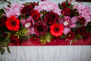 Bouquet of red and pink autumn flowers lies on a dinner table