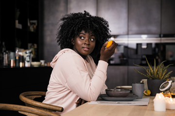 Fototapeta na wymiar Schwarz Frau mit Orange in der Küche