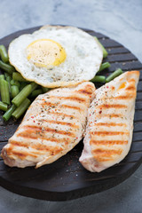Close-up of grilled chicken breasts with fried egg and boiled green beans, selective focus, vertical shot