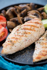Close-up of grilled chicken breasts with fried mushrooms and vegetables, selective focus