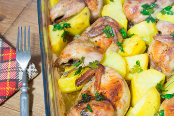 Quail meat baked in the oven. Freshly cooked quail with a side dish of new potatoes and parsley.