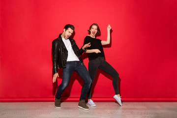 Full length image of playful punk couple dancing in studio