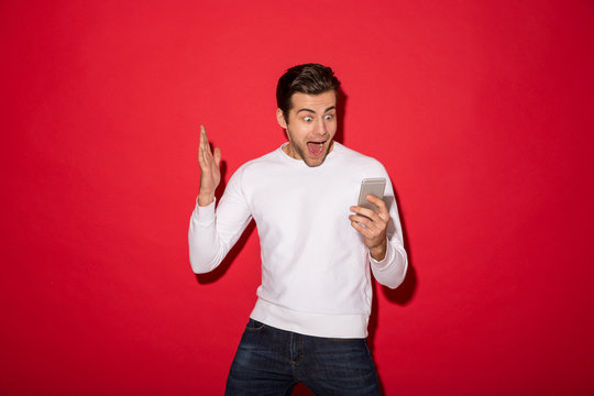 Image of Shocked screaming man in sweater looking at smartphone