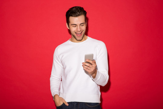 Image of Cheerful man in sweater using smartphone