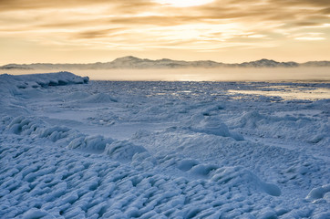Ice floes floating on the fog water in the lake Baikal. Sunset