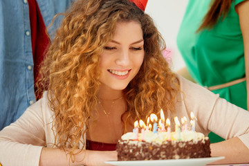 happy woman with candles on birthday cake at party