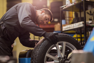 auto mechanic balancing car wheel at workshop