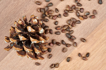 A cone and pine nuts on a background of mahogany boards.