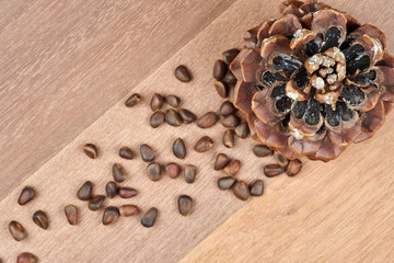 A cone and pine nuts on a background of mahogany boards.