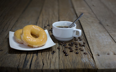 Donut and black coffee  in white dish on old wooden table