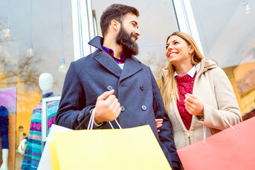 Beautiful young loving couple carrying bags and enjoying together holiday shopping
