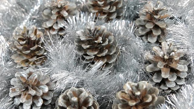 Close-up of the rotation of silver tinsel and silver pine cones. Christmas background, tinsel.