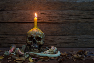 Skull with candle and Dry leaf on old wooden table.
