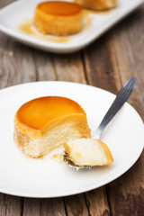 Homemade caramel custard cake in spoon. Served on white plate. Sweet dessert.