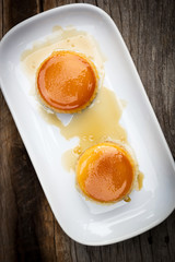 Two homemade caramel custard cake in white plate over wooden table. Top view with dark vignette.
