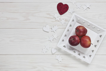 Red apples on white wooden background. Concept for Christmas decor, postcards, menus, invitations. Background, top view.