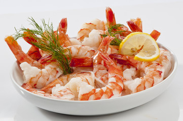 Steamed Jumbo headless shrimps with deli leaves and Lemon on white plate on white background 