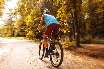 Obraz premium Young man riding a mountain bike on old country road.
