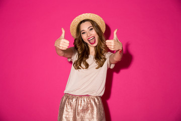 Excited young woman in hat showing thumbs up gesture.