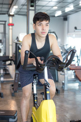 Fototapeta na wymiar Attractive Asian Man on exercise bikes at a gym. Man exercise Concept.