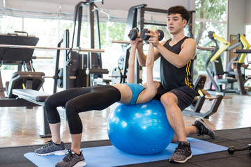 Attractive Asian woman doing exercise with help of her personal trainer. Woman exercise concept.
