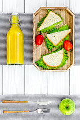 Sandwiches with lettuce and tomatoes for picnic on tablecloth on white wooden background top view copyspace