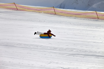 Fototapeta na wymiar Girl downhill on snow tube on ski resort