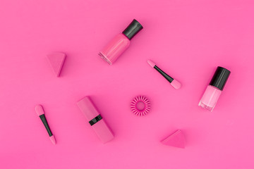 Bright decorative cosmetics. Pink nail polish and lipstick on pink background top view copyspace