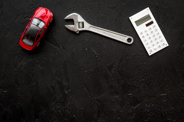 Price of car repair. Wrench near car toys and calculator on black background top view copyspace