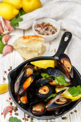 Delicious mussels in white wine with lemon, garlic, herbs and spices. Cilantro and pepper. Seafood. Clams in the shells. Snack for gourmets. Selective focus