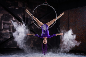 A young, slender girl in a lavender leotard and lilac dreads, doing gymnastics on the air ring, the...