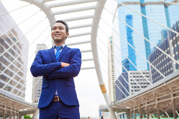 Businessman standing with cross one's arm , with office building background - business success, achievement, and win concepts