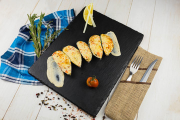 Ready mussels on a stone board, with a wooden background and a linen towel. herbs spices lemon