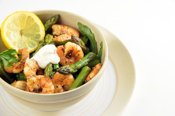 salad from prawn shrimp, green asparagus and lemon slice in a bowl on a plate, corner background isolated on white, festive appetizer or buffet snack