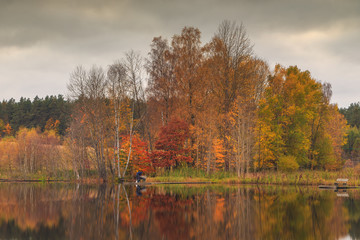 Fisherman on the lake. Autumn colors on the Stone Lake, Poland