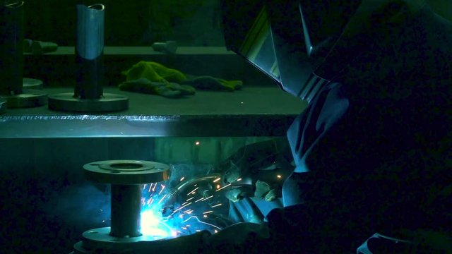 Welding work in slow motion. Welder is welding a water pipes in the factory