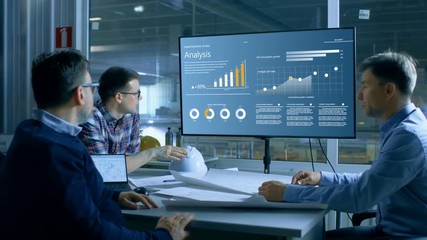 Chief Industrial Engineer Has Meeting with Management and Executives in the Heavy Industry Factory Have Quarterly Meeting Room, They Look at Production Statistics on a Big Screen. - Powered by Adobe