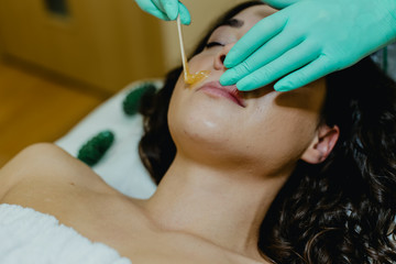 Sugaring. The girl beautician deals on a client's face the sugar wax.