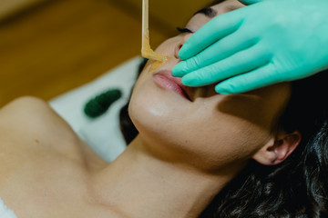 Sugaring. The girl beautician deals on a client's face the sugar wax.