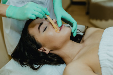 Sugaring. The girl beautician deals on a client's face the sugar wax.