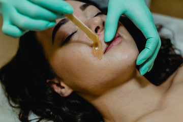 Sugaring. The girl beautician deals on a client's face the sugar wax.