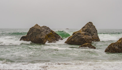 Fototapeta na wymiar Waves Crash Against Rocks in Pacific Ocean