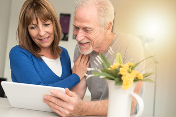 Modern mature couple using tablet, light effect