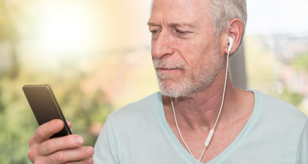 Portrait of mature man listening music with earphones, light effect