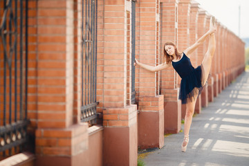 Ballerina dances ballet in pointe shoes and pack on streets of city.