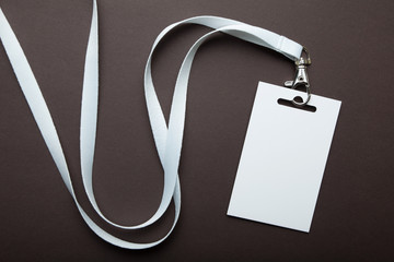 Empty businessman name card on a lanyard. Identification tag isolated on brown background. Mockup.